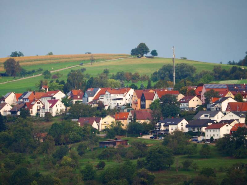 Eine Ortsansicht auf Diegelsberg, eingebettet in Felder, Wiesen, Wald und auf einem Hügel.