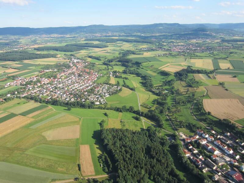 Luftaufnahme von Sparwiesen, inmitten von Feldern, Wiesen und Wäldern im Sommer.