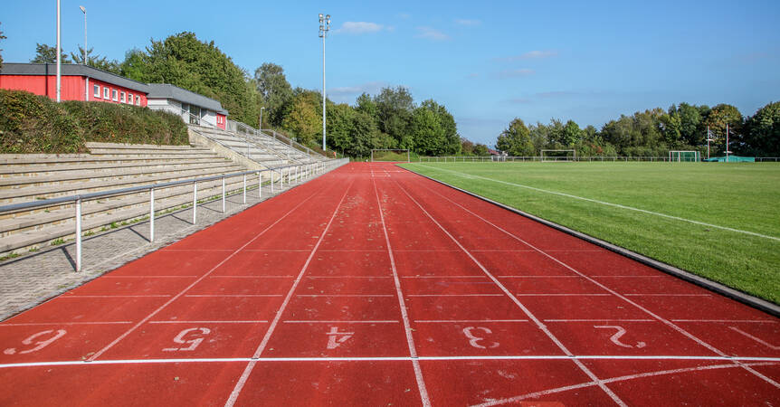Die rote Tartanbahn im Haldenberg-Stadion, rechts davon der Rasen und links die Tribüne.