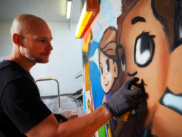 Ein Grafitti-Sprayer besprüht eine Wand
