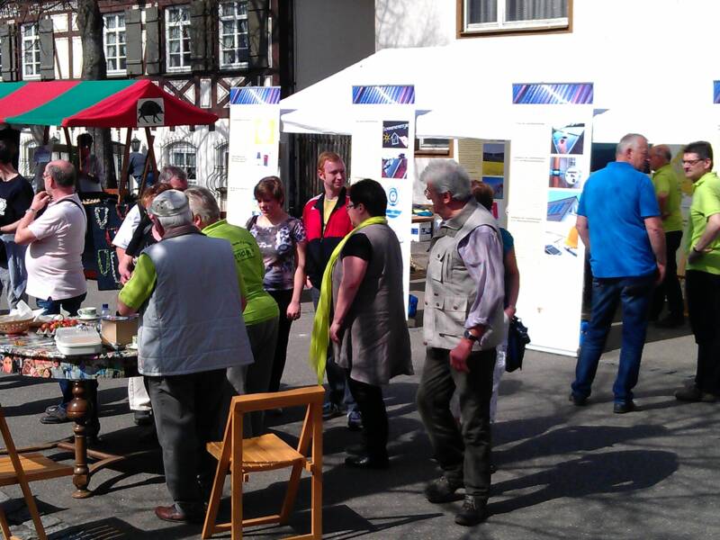An einem Frühlingstag stehen viele Menschen vor dem Berchtoldshof und interessieren sich für nachhaltige Themen, zum Beispiel Solarenergie. Es gibt Schautafeln zum Betrachten.