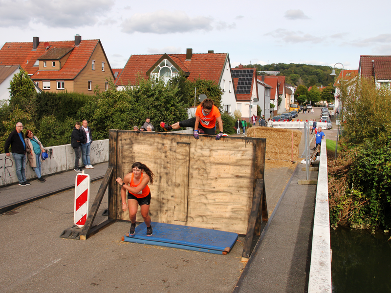 Auf einer Brücke stehen Holzwände als Hindernisse, die von Extremsportlern bewältigt werden.