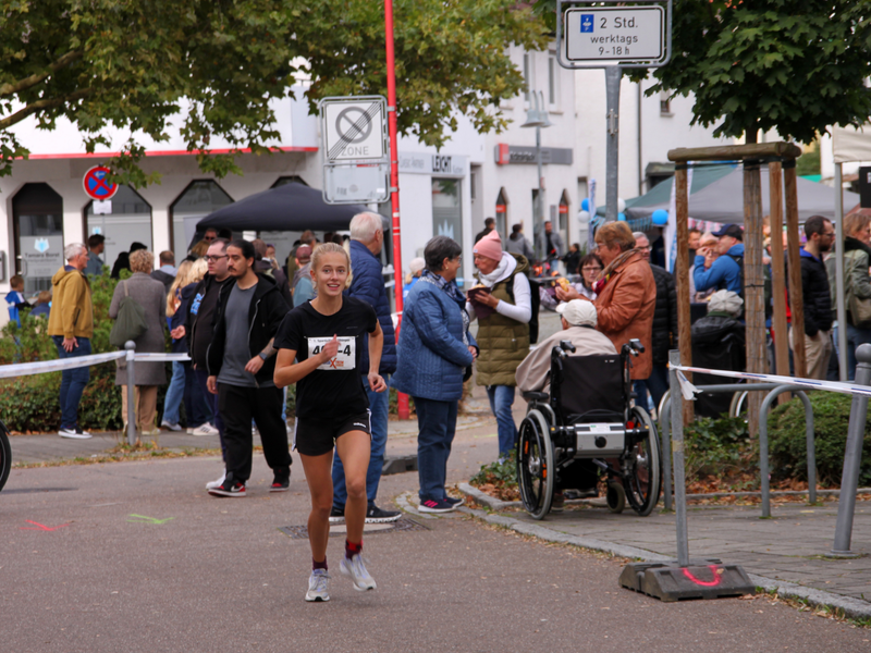 Eine blonde Läuferin rennt an Passanten vorbei.