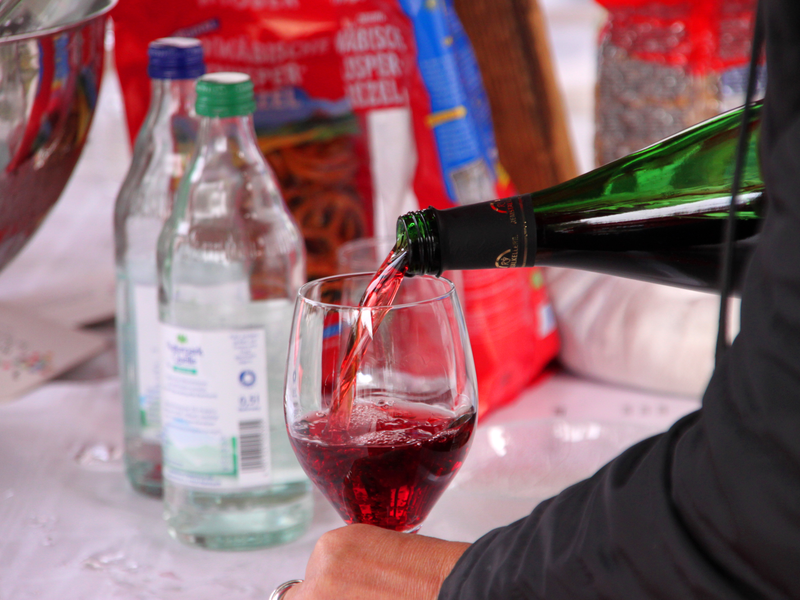 In ein Weinglas wird Rotwein eingeschenkt.