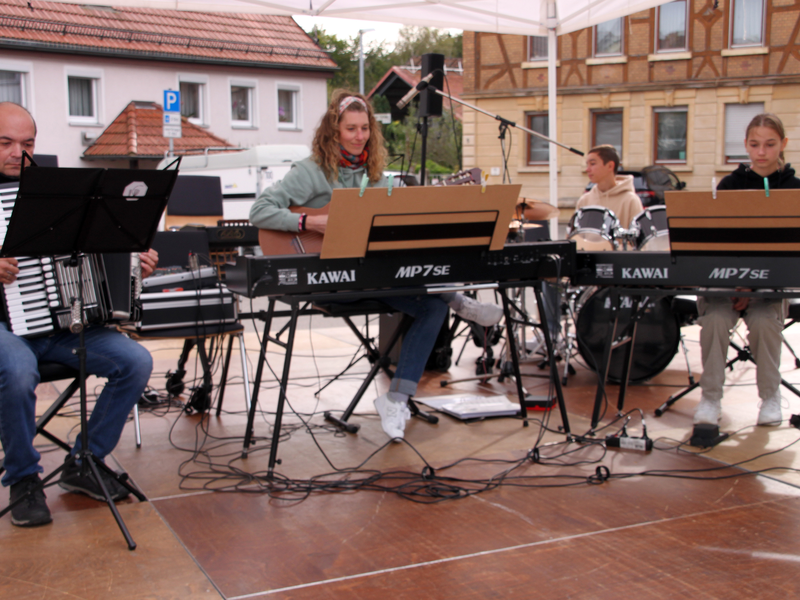 Eine Musikergruppe spielt auf ihren Instrumenten auf einer Bühne.