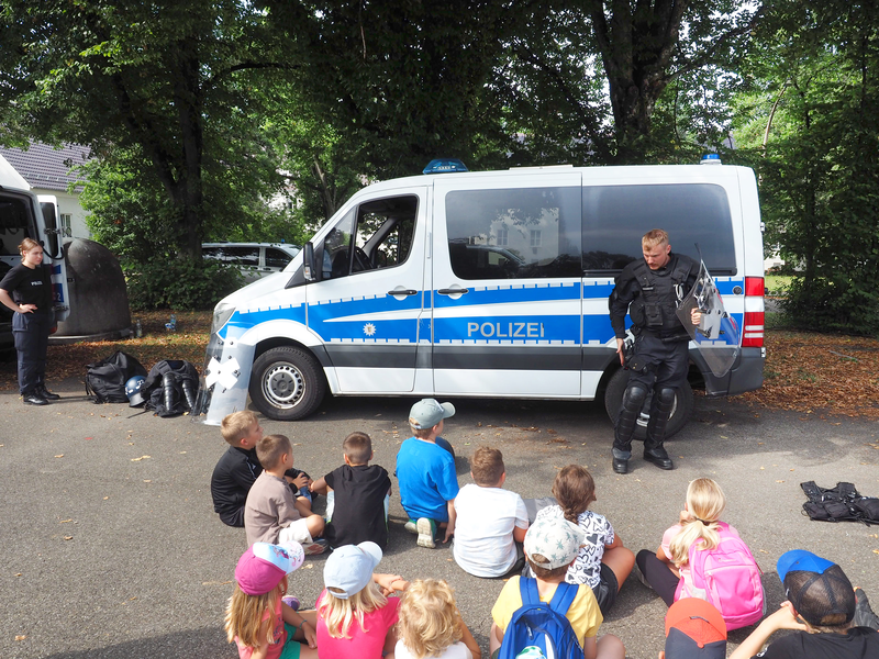 Ein Bereitschaftspolizist erklärt den Kindern seine Ausrüstung: von Schutzbekleidung bis hin zu Waffen. 