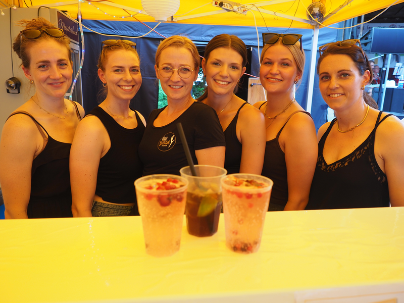 Junge Frauen von der Showgruppe Oldbutgold stehen an einem Tresen, vor ihnen sind drei Becher mit Getränken.