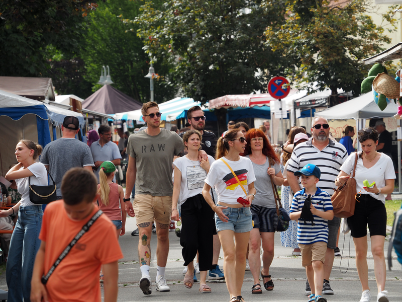 Passanten flanieren in sommerlicher Kleidung vorbei an Festständen beim Kandelhock