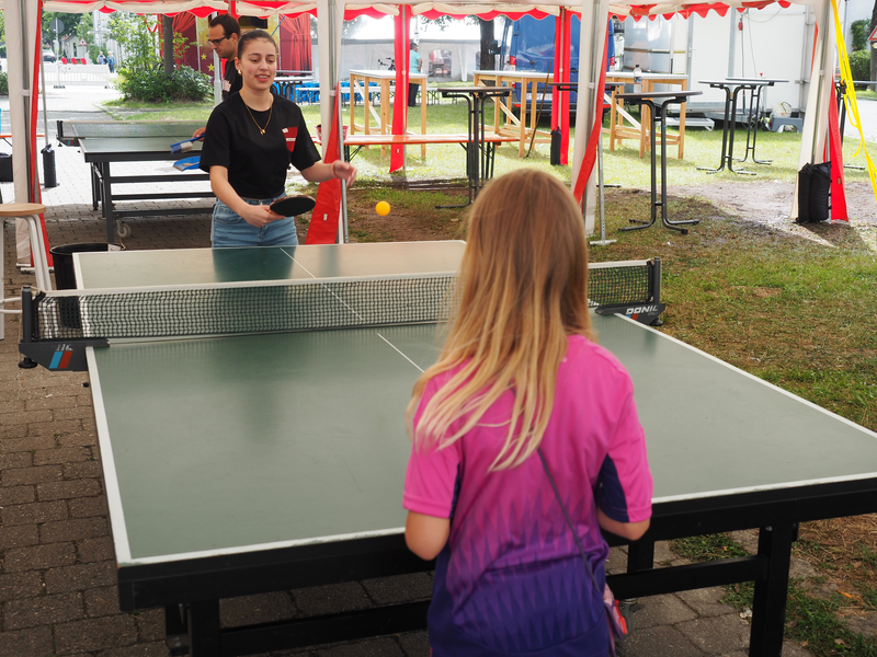 Ein Mädchen im Deutschland-Trikot steht an einer Tischtennisplatte und spielt mit einer jungen Frau Tischtennis.