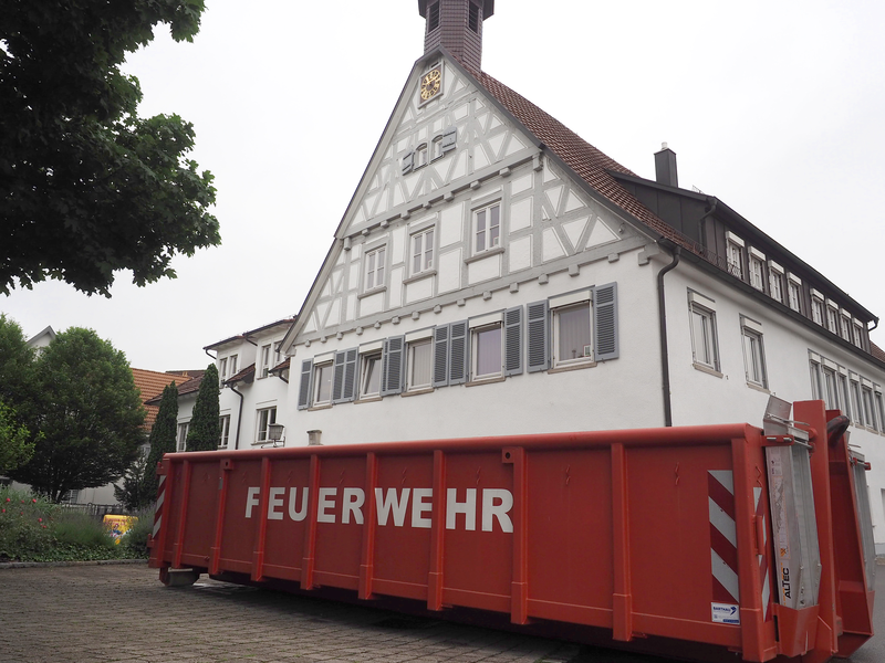Ein roter Container steht vor dem Fachwerkgebäude des Rathauses.