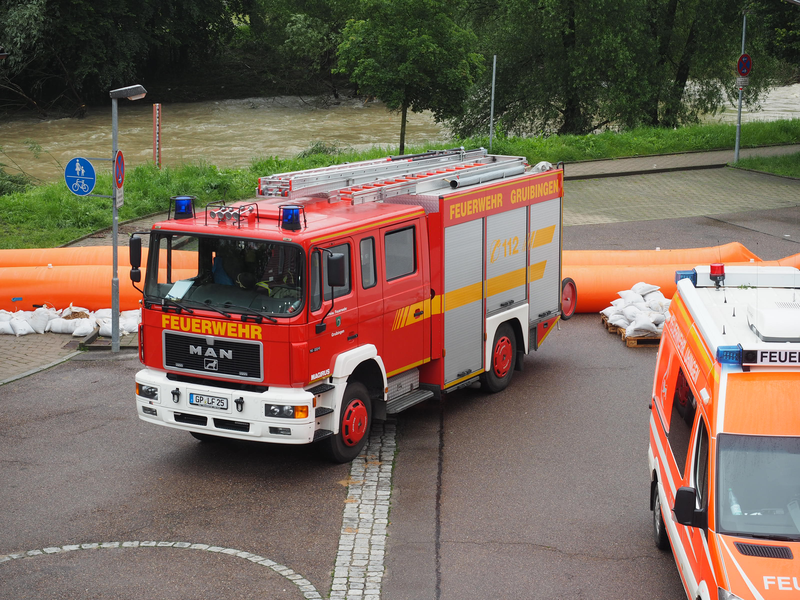 Einsatzfahrzeuge der Feuerwehr stehen auf dem Hof, im Hintergrund ist die Fils.