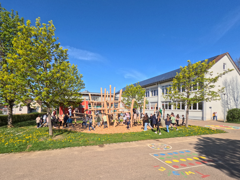 Kinder spielen auf einem Abenteuerspielplatz neben der Grundschule im Stadtteil Sparwiesen bei sonnigem Wetter.